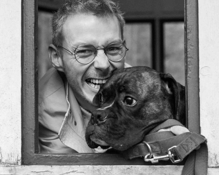 Mann, der seinem Hund liebevoll ins Ohr beißt